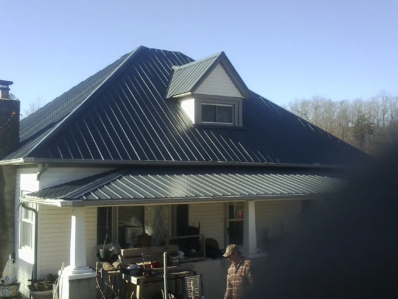 Dark blue standing seam metal roof with a dormer above a front porch in Yatesboro