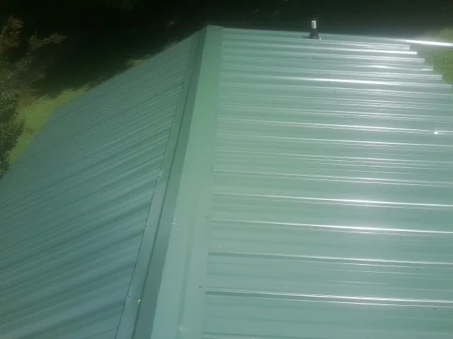 New green metal panels meeting at the ridge of a roof — Flat Roof Repair work by our crew in Yatesboro