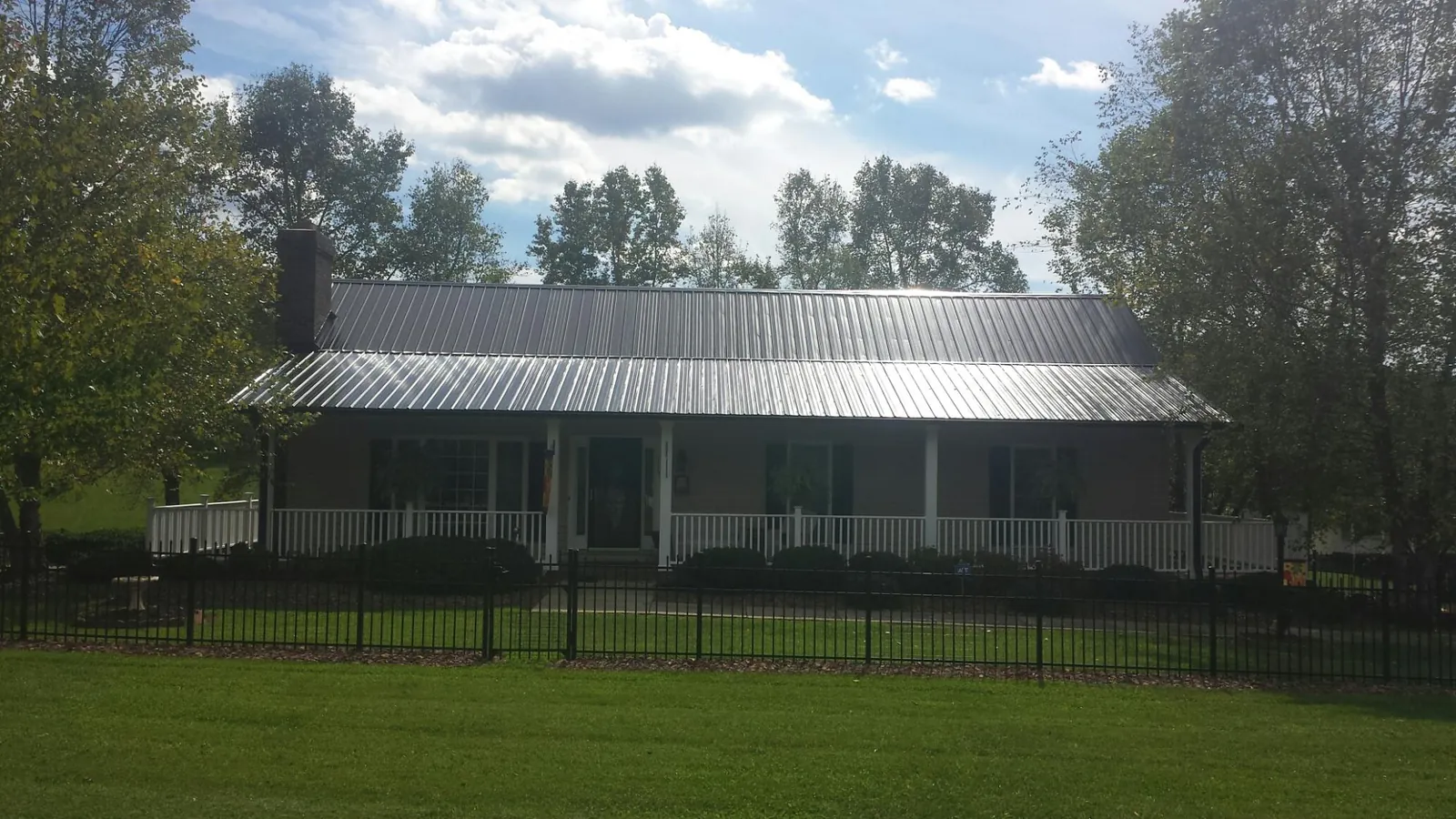 Gray metal roof on a brick ranch with a full width front porch — Gutter Guard Installation work by our crew in Yatesboro