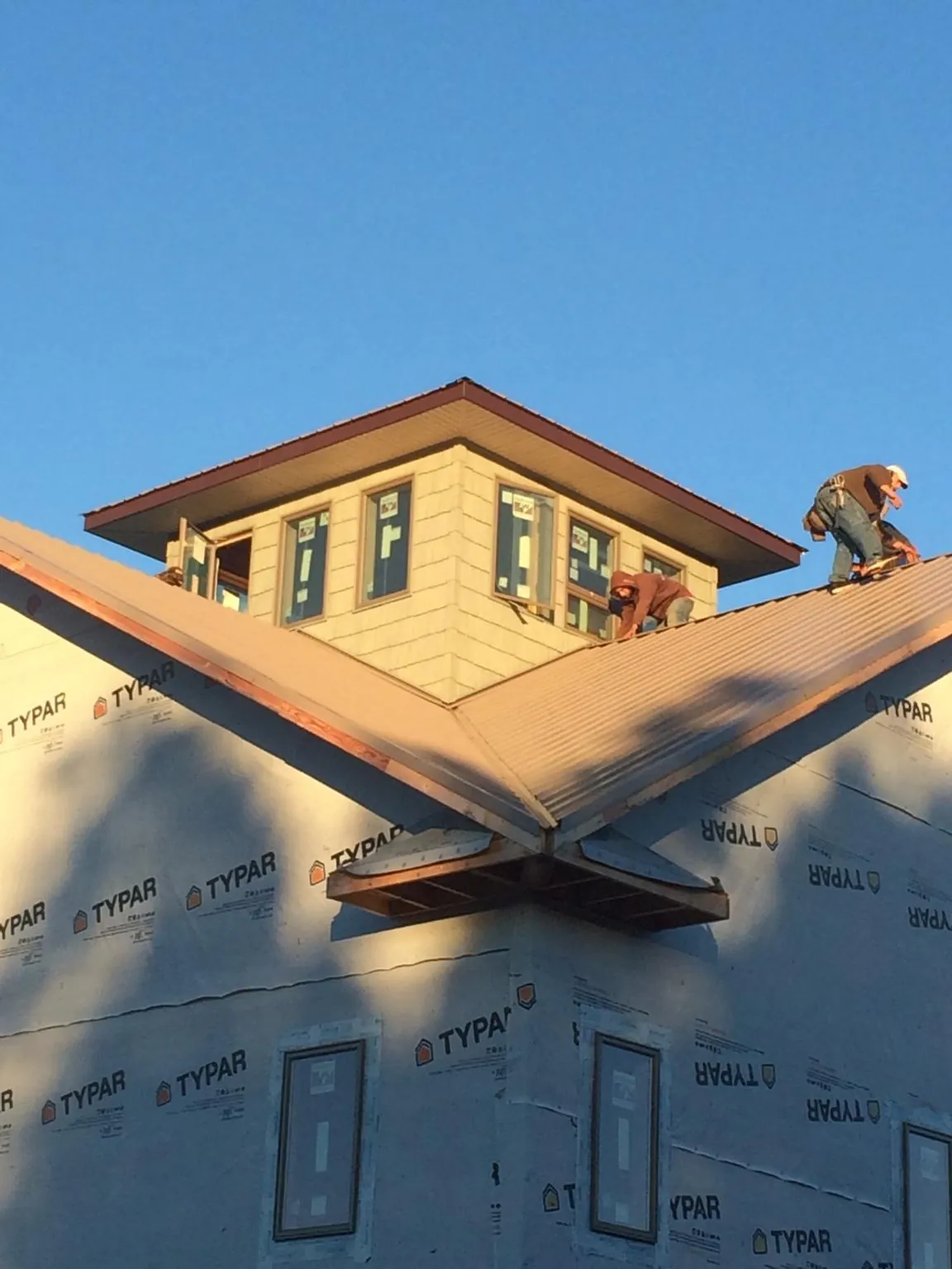 Roofers working around a rooftop cupola on a new metal roof at sunset — Roof Waterproofing in Yatesboro by Roofing Brothers